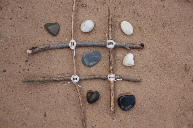 stones in a noughts and crosses frame made from sticks picture